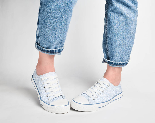 Vrouwelijke benen Kortom jeans en sneakers staan op een witte pagina - Foto, afbeelding