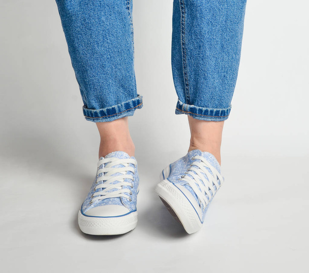 Kobiece nogi w skrócie dżinsy i Adidasy stanąć na białym tle - Zdjęcie, obraz