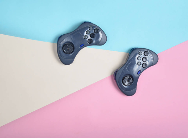 Two gamepads on a multi-colored pastel background. Top view, minimalis - Photo, Image