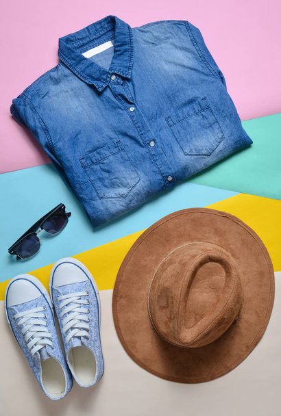 Ropa y accesorios de moda para mujer. Camisa de mezclilla, zapatillas, sombrero de fieltro, gafas de sol, diseño sobre un fondo de color. Vista superior, plana la
 - Foto, Imagen