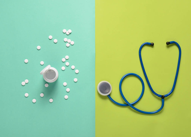Stethoscope and bottle with pills on a colored background, medical concept, top view - Photo, Image