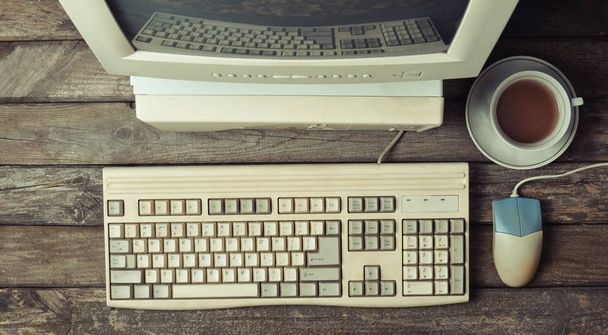 Computador estacionário retro em uma mesa de madeira rústica, espaço de trabalho vintage. Monitor, teclado, mouse de computador, vista superior, flat la
 - Foto, Imagem