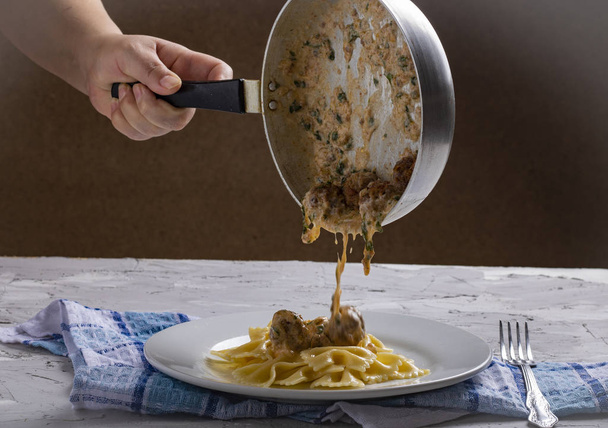 person   with pan putting meatballs on the plate with pasta - Fotoğraf, Görsel