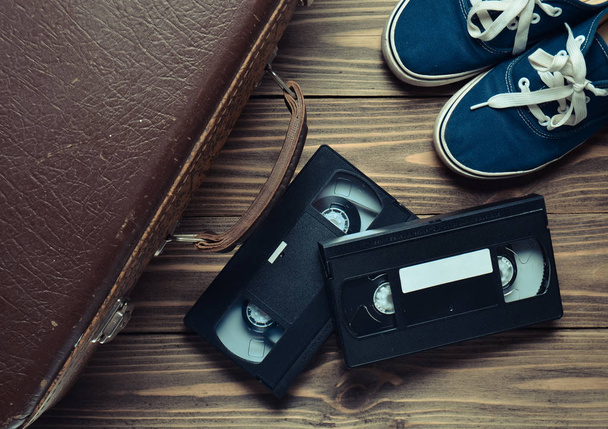 Vintage lederen koffer, videocassettes en sneakers op een houten vloer. Top Vie - Foto, afbeelding