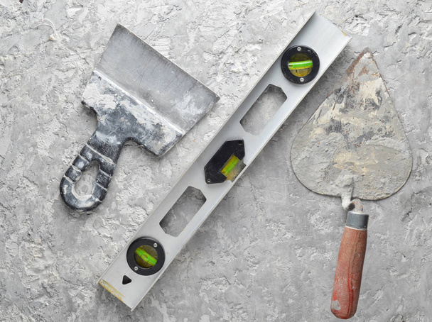 Building tools on a gray concrete background. Spatula, trowel, level, level, top vie - Photo, Image
