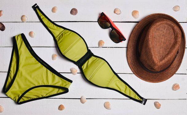Fürdőruha, kalap, napszemüveg, tengeri kagylókból, fehér fa felületre. Felkészülés a strand szezon. Nyári idő. Szemközti nézet. - Fotó, kép