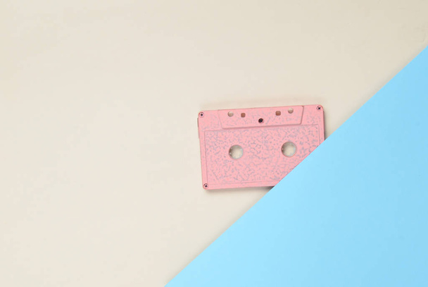 Cassette de audio sobre un fondo de papel de color. Tecnología de medios retro años 80. Música, entretenimiento. Vista superior. minimalismo tren
 - Foto, imagen