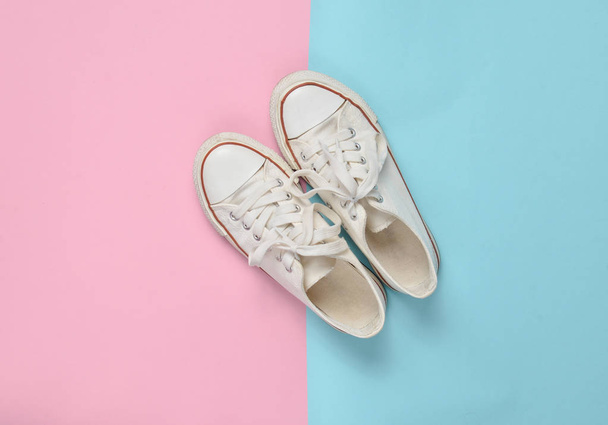 Viejas zapatillas retro con cordones blancos sobre un fondo pastel rosa azulado. Minimalismo. Vista superior
 - Foto, imagen