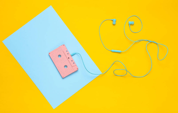 Cassette de audio y auriculares sobre un fondo azul pastel amarillo. Concepto musical. Estilo retro. Minimalismo. Top Vie
 - Foto, Imagen