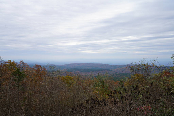 schilderachtig uitzicht op heuvels en bewolkte hemel over herfst bomen - Foto, afbeelding