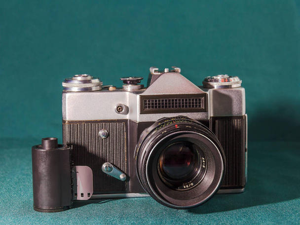 Vieil appareil photo reflex avec objectif interchangeable et film 35 mm sur fond vert-bleu
 - Photo, image