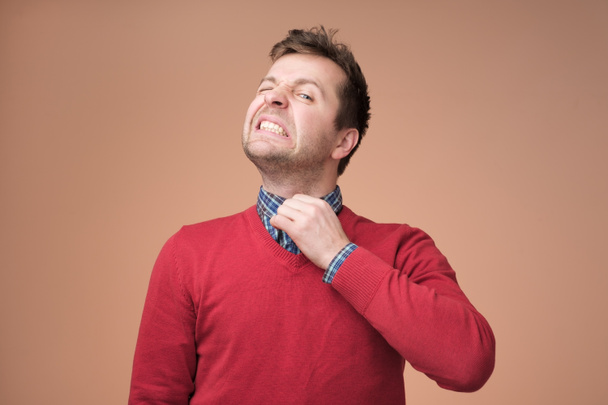 Молодий європейський чоловік у червоному светрі некомфортний
. - Фото, зображення