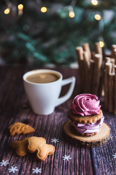 Close up of homemade pink and purple zephyr or marshmallow in powdered sugar with white mug on wooden with abstract bokeh background. Black currant, blueberry marshmallows. Christmas or New Year composition. Christmas card. - Photo, Image