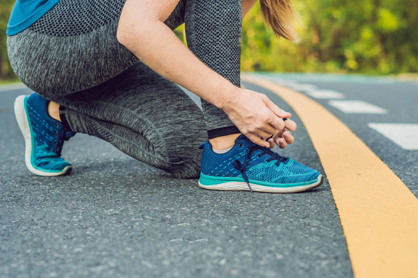 Жінка-бігун зав'язує взуття, готуючись до бігу на вулиці. Молода бігунка-ремінь готується до тренувань. Спортивний спосіб життя
 - Фото, зображення