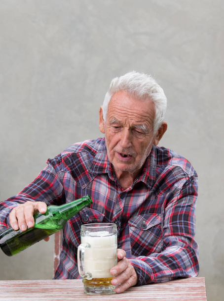 Idős részeg az ember ül az asztalnál, és iszik sört - Fotó, kép