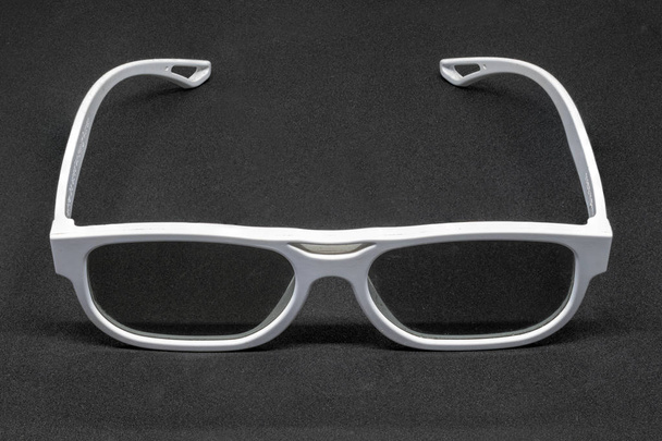 Белые трехмерные очки на темно-сером фоне
 - Фото, изображение