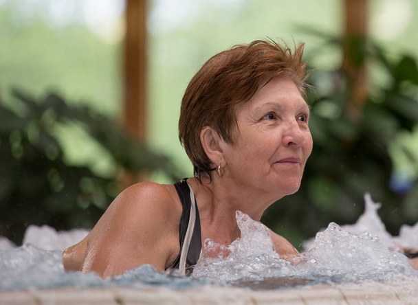 Mujer mayor disfrutando en piscina con agua caliente en balneario
 - Foto, Imagen