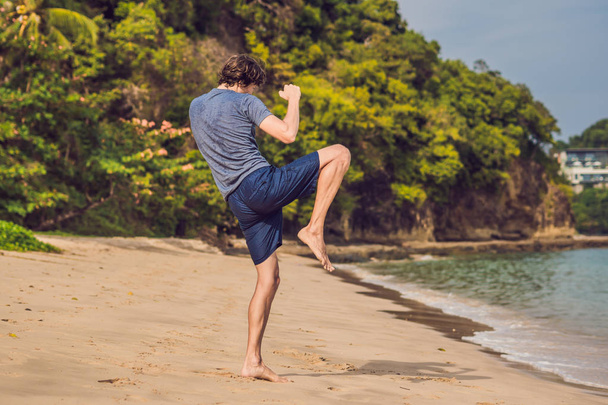 young male working out on beach, sporty man doing exercises - Foto, afbeelding