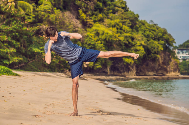 jonge man uit te werken op strand, sportieve man doen oefeningen - Foto, afbeelding