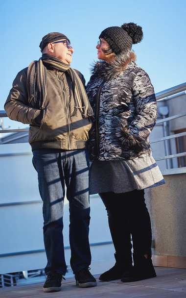 felices jubilados felices pareja calurosamente vestida de pie en el balcón
. - Foto, imagen