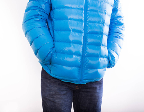 Mladý muž v modrá péřová bunda a džíny izolovaných na bílém pozadí - Fotografie, Obrázek
