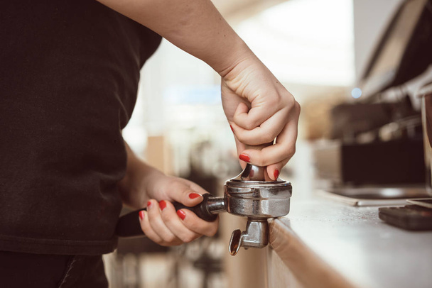 Barista presiona café molido usando manipulación. Vista de cerca en las manos
 - Foto, imagen