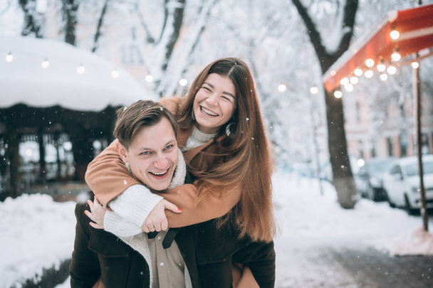 όμορφο νεαρό ζευγάρι έχει τη διασκέδαση σε ένα χιονισμένο δρόμο - Φωτογραφία, εικόνα