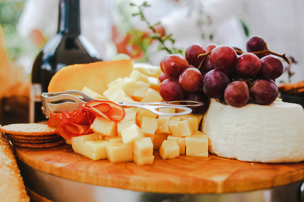チーズの盛り合わせとブドウ、サラミ、クラッカー - 写真・画像