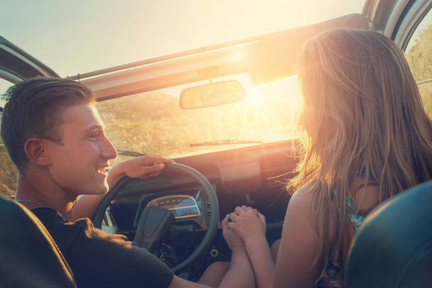 Pareja feliz en un coche disfrutando de la puesta del sol
. - Foto, imagen