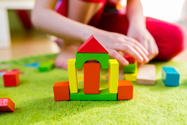 Kleines Kind spielt mit Holzklötzen auf grünem Teppich - geringe Schärfentiefe - Foto, Bild