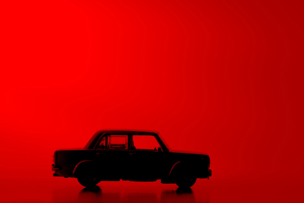 Carro de brinquedo silhueta em um fundo vermelho vibrante
. - Foto, Imagem