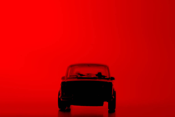Carro de brinquedo silhueta em um fundo vermelho vibrante
. - Foto, Imagem
