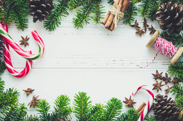 Karácsonyi keret fenyő fa ágai, természetes dekorációk és édességet vesszők, a hely a szöveg fehér háttéren. Kellemes karácsonyi ünnepeket és boldog új évet. Xmas koncepció. Felülnézet. Lapos feküdt. Másolja a hely. - Fotó, kép