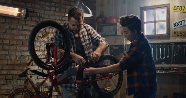 Πατέρας και γιος επισκευή ένα ποδήλατο σε ένα γκαράζ - Φωτογραφία, εικόνα