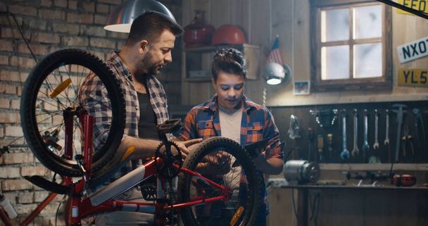Vater und Sohn sprechen über Reparatur von Fahrrädern - Foto, Bild