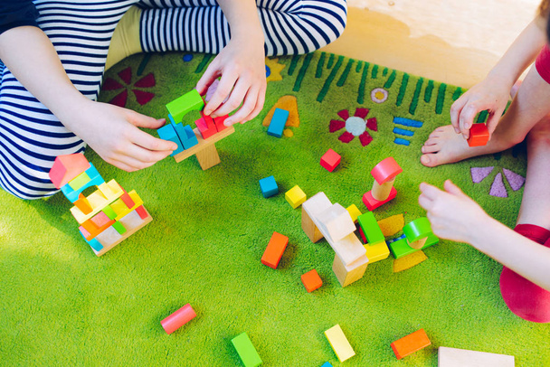 Klein kind spelen met houten blokken op groene tapijt - ondiepe scherptediepte - Foto, afbeelding