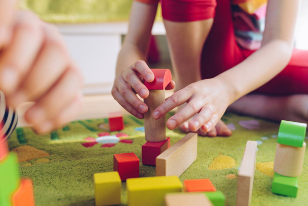 Klein kind spelen met houten blokken op groene tapijt - ondiepe scherptediepte - Foto, afbeelding
