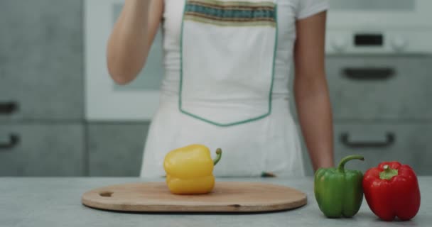 Желтый перец на современной кухне разрезает большим ножом женщина-повар
. - Кадры, видео