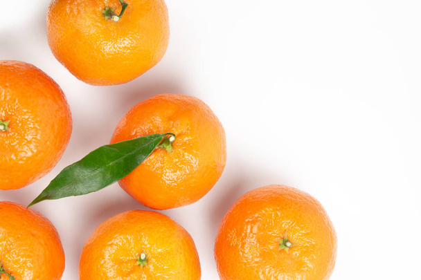 Érett narancs-mandarin, zöld levelek, a fehér háttér, copyspace és egy mandarin központjában a középpontban - Fotó, kép