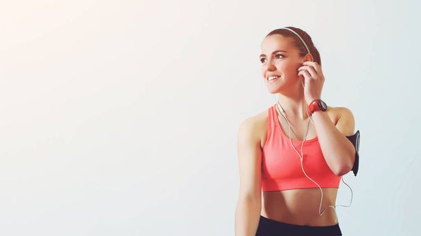 Young fitness woman looking aside, listen music while taking a break. Active girl using smartphone in fitness gym. Fitness and healthy lifestyle concept. Female in sports clothing have relaxing - Foto, Bild