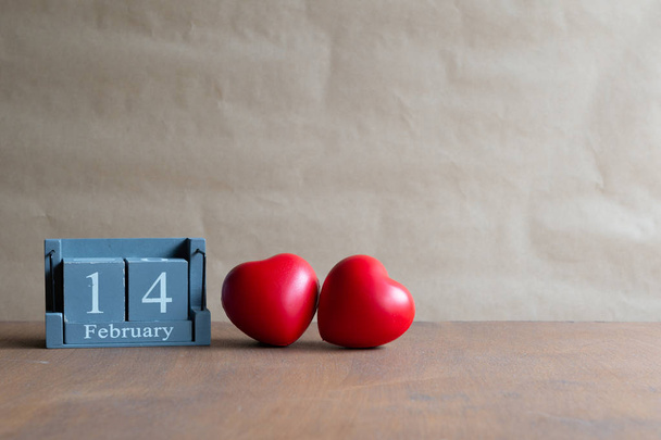 Το ξύλινο ημερολόγιο της 14ης Φεβρουαρίου διαθέτει δύο κόκκινες καρδιές τοποθετημένες δίπλα-δίπλα με φυσικό φόντο.Ημέρα του Αγίου Βαλεντίνου. - Φωτογραφία, εικόνα