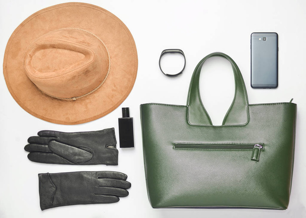 Γυναικεία αξεσουάρ και gadget σε λευκό φόντο. Τσάντα, καπέλο, γάντια, smartphone, έξυπνο ρολόι, μπουκάλι άρωμα. Συλλογή φθινόπωρο άνοιξη. Το top view. Επίπεδη θέσει - Φωτογραφία, εικόνα