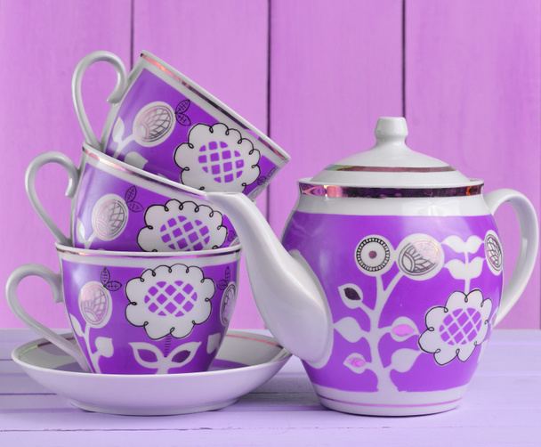 A stack of ceramic retro cups with red patternsand teapot on a pink wooden table against a blue wooden wall background, pastel color tren - Photo, Image