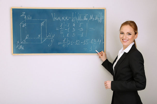 Portrait of teacher woman writing on the chalkboard in classroom - Fotoğraf, Görsel