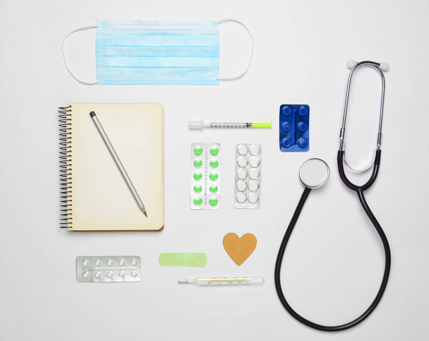 Medical cardiology equipment on a white background. Stethoscope, tablet,pills, thermometer, notebook, syringe. Medical concept, top view, flat lay styl - Fotografie, Obrázek