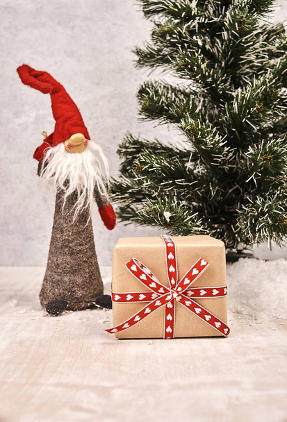 закрыть вид на рождественскую подарочную коробку, завернутую праздничной лентой рядом с гномом и елкой чирм
 - Фото, изображение