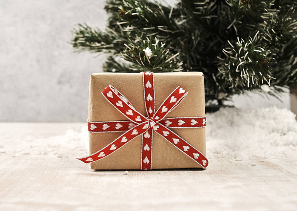 close up vista da caixa de presente de Natal envolto por fita festiva perto da árvore de natal
 - Foto, Imagem