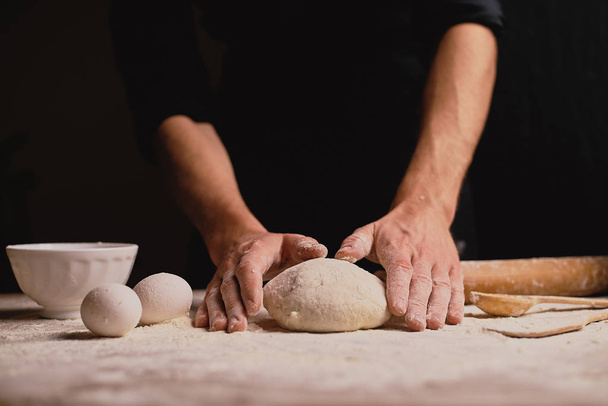 mid section of man kneading dough on wooden table  - Fotografie, Obrázek