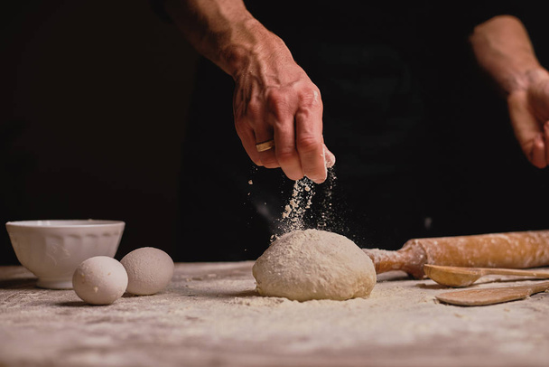 colpo ritagliato di mano maschile setacciando la farina sulla pasta sul tavolo di legno
  - Foto, immagini