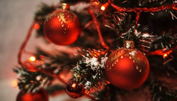 schöner Weihnachtsbaum mit roten, glänzenden Kugeln und beleuchteter Girlande  - Foto, Bild